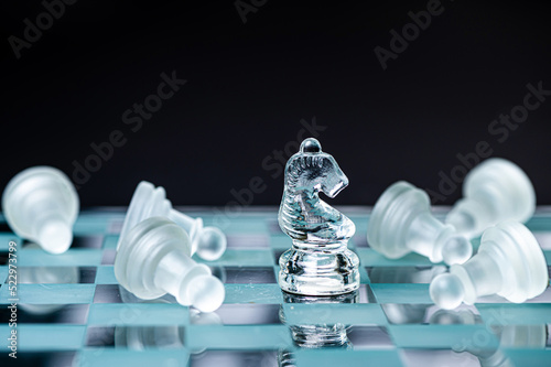 transparent glass chess on dark background, selective focus on horse piece, close-up photo