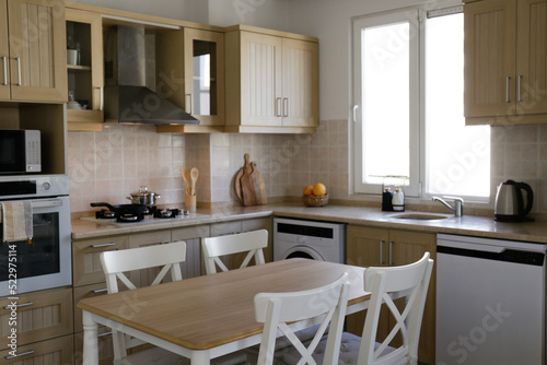 Stylish wooden kitchen with a window, built-in appliances and small beige tile. Close up, copy space, background.