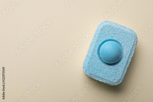 Water softener tablet on beige background, top view. Space for text