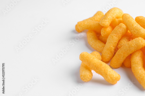 Heap of tasty cheesy corn puffs on white background, space for text