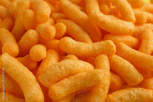 Tasty cheesy corn puffs as background, closeup