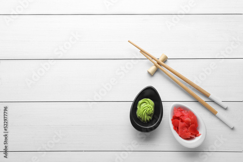 Swirl of wasabi paste, pickled ginger and chopsticks on white table, flat lay. Space for text