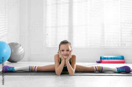 Cute little girl doing gymnastic exercise indoors. Side split
