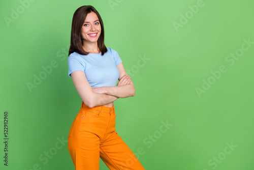 Portrait of adorable satisfied girl beaming smile folded arms empty space isolated on green color background © deagreez
