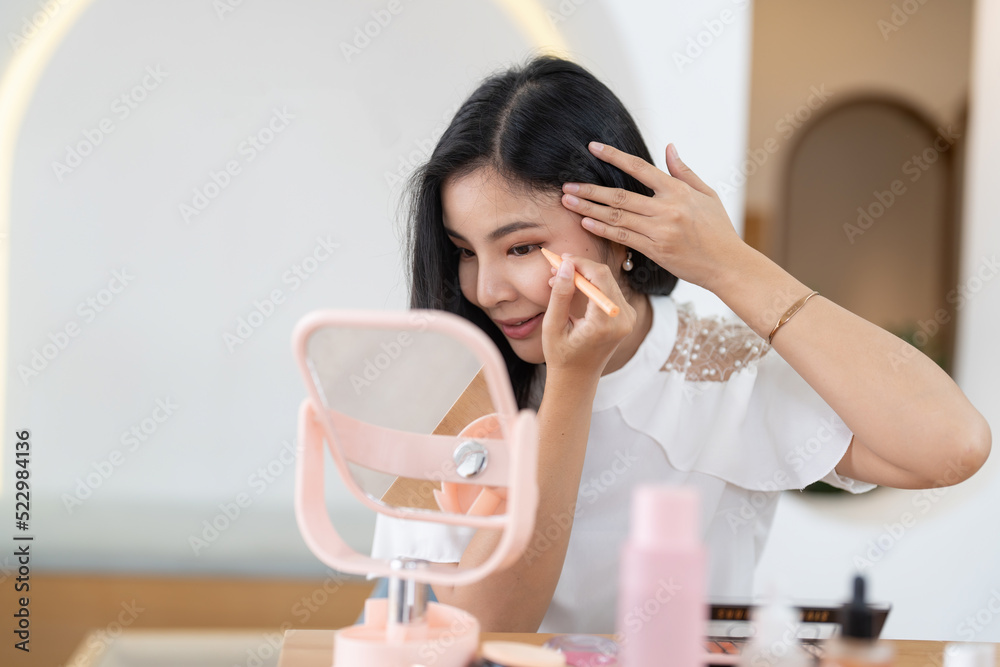 Beauty blogger concept, beautiful and cute asian young woman, girl makeup face by applying brush for eyes on eyebrow, eyeshadow looking at the mirror at home. Female look with natural fashion style. Beauty blogger concept, beautiful and cute asian young woman, girl makeup face by applying brush for eyes on eyebrow, eyeshadow looking at the mirror at home. Female look with natural fashion style.