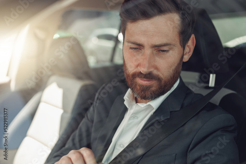 Handsome businessman in grey suit is riding behind steering wheel of car © Kostiantyn