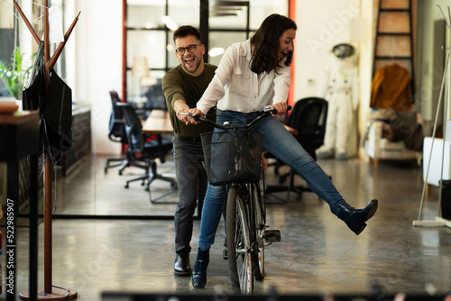 Colleagues in office. Businesswoman and businessman with bicycle. Two friends having fun together.