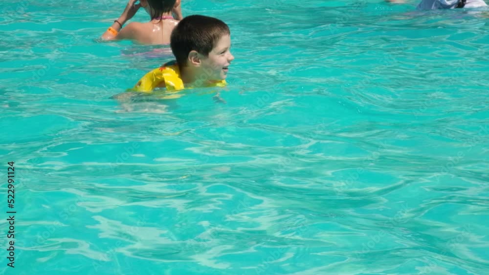 A 5-year-old boy is learning to swim in an inflatable vest in a pool. A 5-year-old boy is learning to swim in an inflatable vest in a pool.