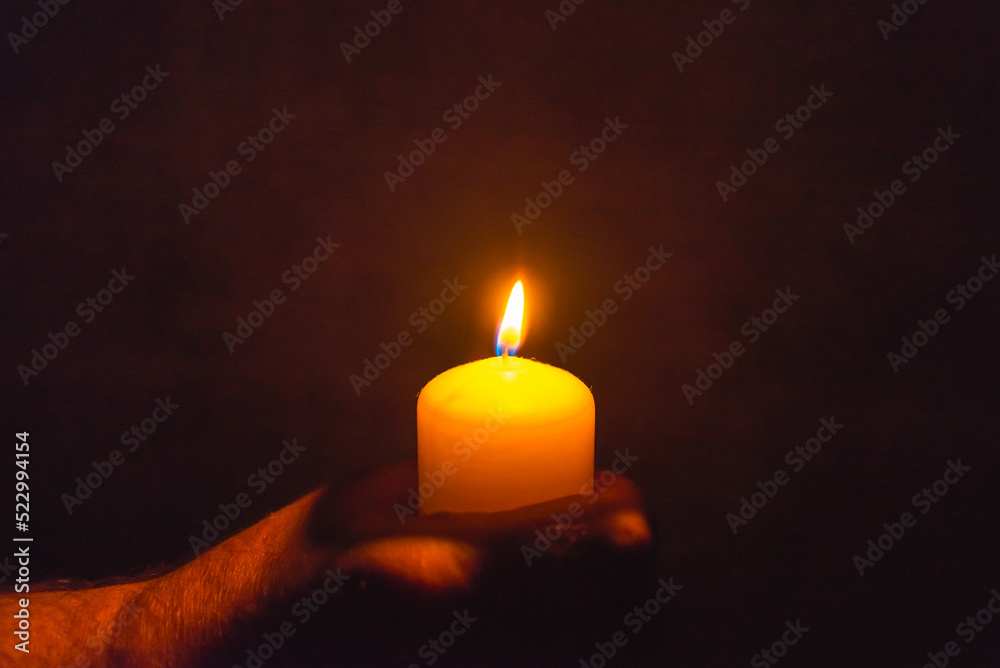 Burning candle in a mans hand religion concept.Candle in hands on a dark background. Burning candle in a mans hand religion concept.Candle in hands on a dark background.