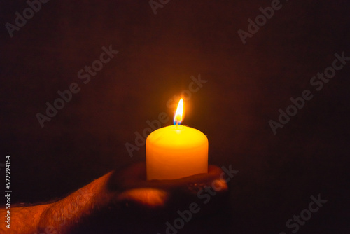 Burning candle in a mans hand religion concept.Candle in hands on a dark background.