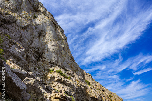 Bottom view of huge rock. Clouds in blue sea. Mountain.