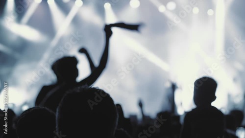 A blurry and illuminated dancing crowd at a concert. Silhouette of people at a party during the festival. People wave their hands, greeting their idol - musician, singer, rock star. The concert square