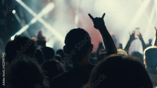 A blurry and illuminated dancing crowd at a concert. Silhouette of people at a party during the festival. People wave their hands, greeting their idol - musician, singer, rock star. The concert square