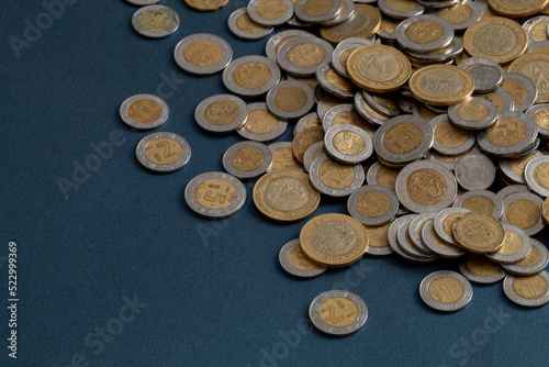 pile of mexican pesos coins  on a blue surface  with copy space