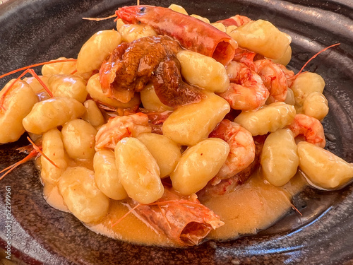 Gnocchetti di patate con gamberi rossi e riccio di mare serviti in un piatto nero in un ristorante di pesce  photo