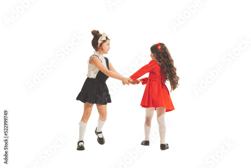 Studio shot of little happy girls in retro style outfit, fashion of 70s, 80s years isolated on white background. Concept of art, friendship, hope, youth