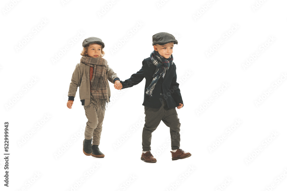Two preschool age boys, fashionable kids wearing autumn retro clothes strolling isolated over white background. Concept of childhood, vintage fashion style Two preschool age boys, fashionable kids wearing autumn retro clothes strolling isolated over white background. Concept of childhood, vintage fashion style