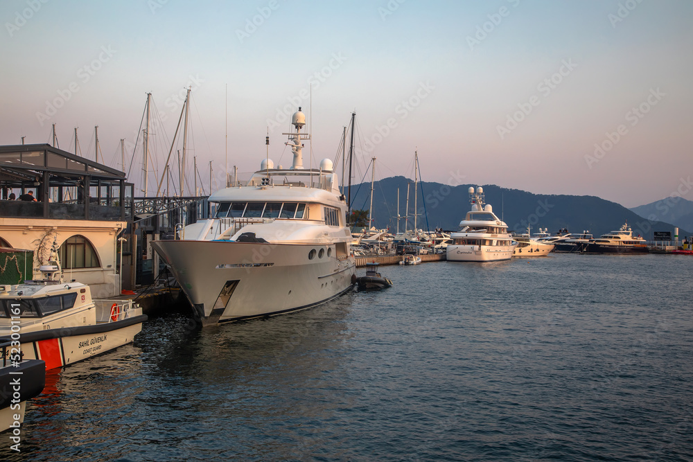 White yachts are in the bay at sunset. Calm sea. Mountains in the background. Beautiful evening in Marmaris.