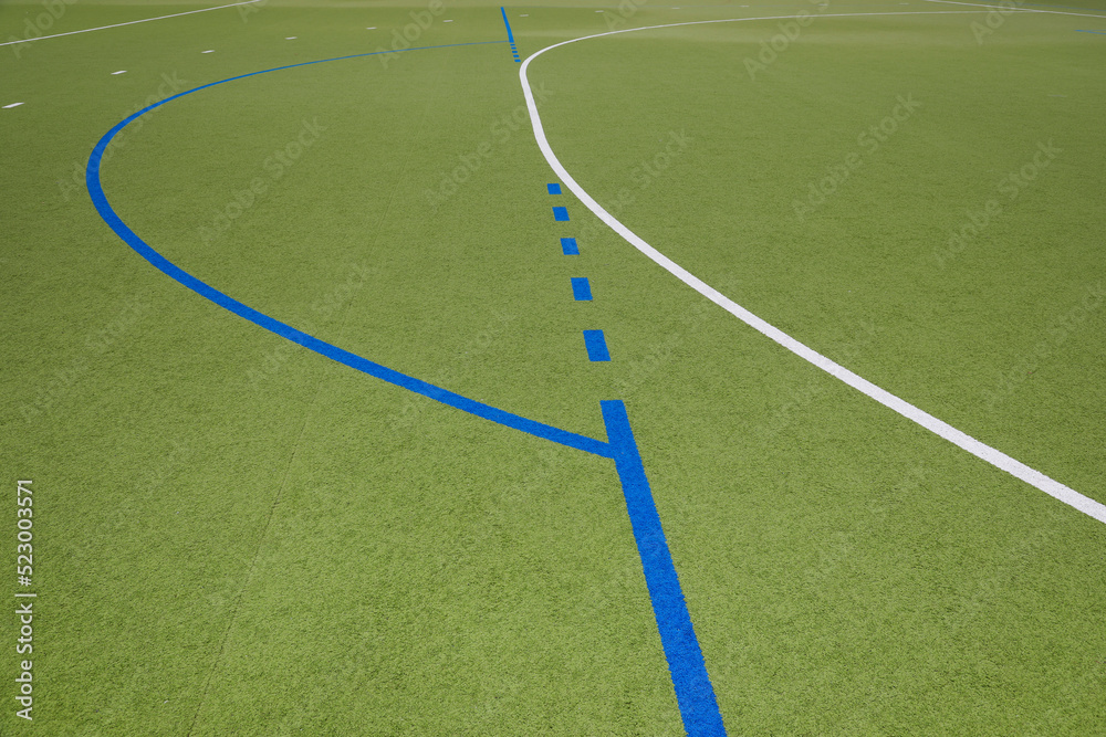 Fototapeta premium Lines in white and blue of a grass hockey field, no person 