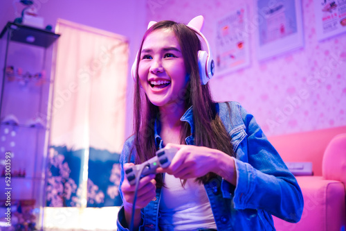 Young asian woman is using virtual reality headset. Neon light studio portrait. Concept of virtual reality  simulation  gaming and future technology.Asian woman play game in living room.