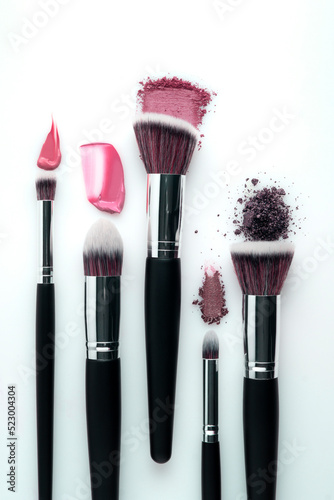 Creative concept beauty fashion photo of cosmetic product make up brushes kit with smashed lipstick eyeshadow on white background.