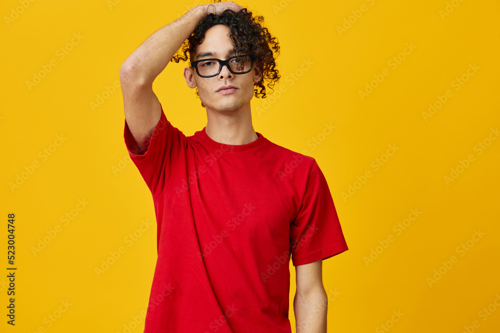 Lovely myopic young student man in red t-shirt funny eyewear looks at camera posing isolated on over yellow studio background. The best offer with free place for advertising. Education College concept Lovely myopic young student man in red t-shirt funny eyewear looks at camera posing isolated on over yellow studio background. The best offer with free place for advertising. Education College concept