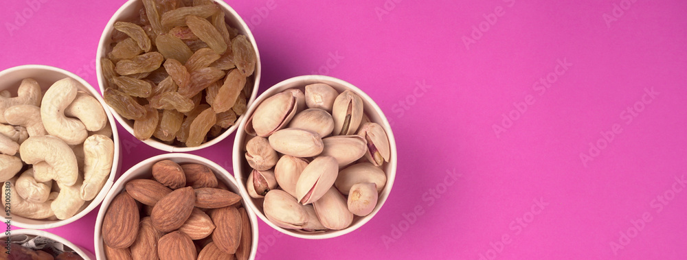 A variety mix of dried fruits and nuts on a pink background. Selective focus.Concept of Healthy fitness super food. A variety mix of dried fruits and nuts on a pink background. Selective focus.Concept of Healthy fitness super food.