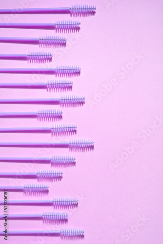 Creative concept beauty photo of lashes extensions brush on pink background.