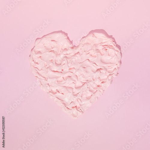 Heart from whipped cream on pink background. Love is sweet concept.