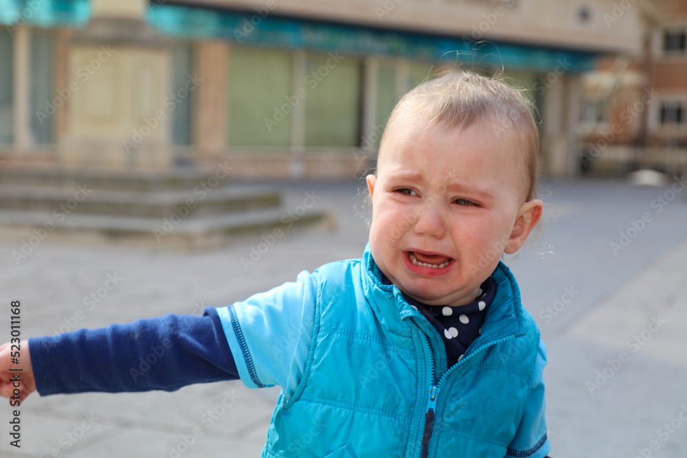 Portrait of Caucasian baby crying on the street. Upset child