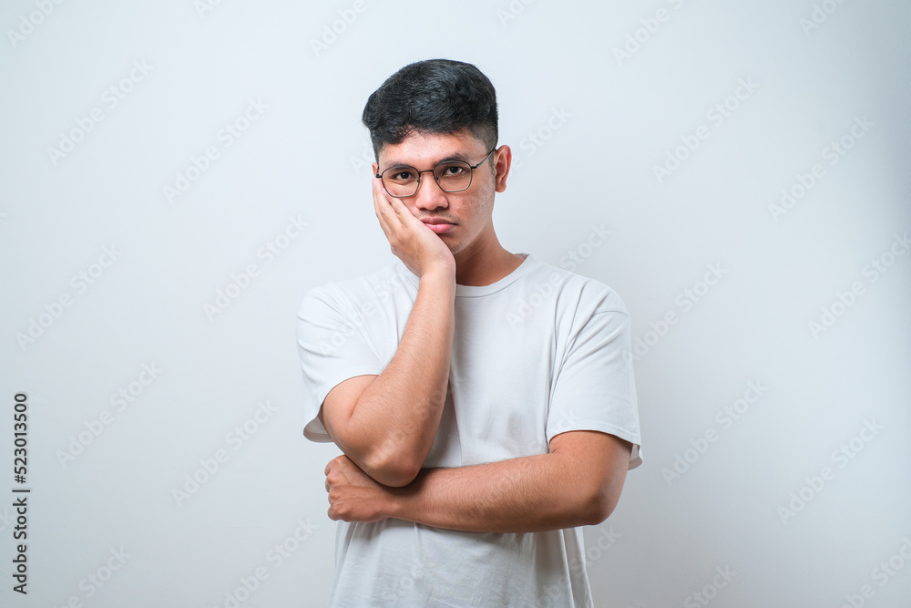 Young asian man wearing casual shirt and glasses thinking looking tired and bored with depression problems with crossed arms. Young asian man wearing casual shirt and glasses thinking looking tired and bored with depression problems with crossed arms.