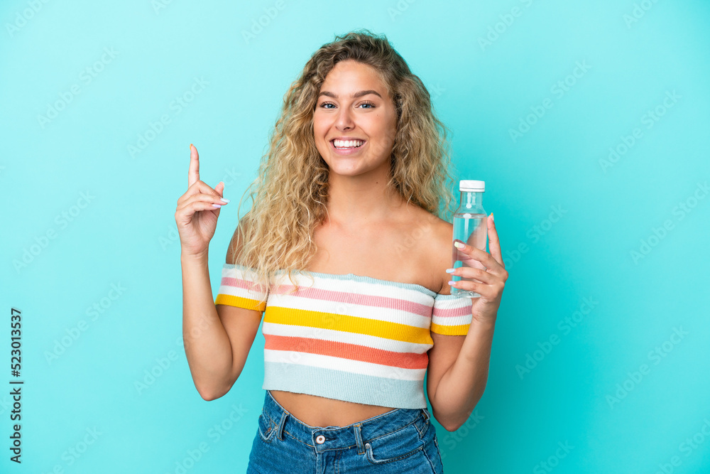 Young blonde woman with a bottle of water isolated on blue background showing and lifting a finger in sign of the best