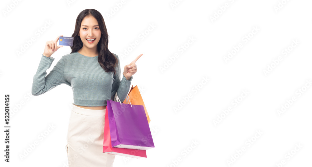 Trendy young Asian woman hold plastic credit card and shopping bags pointing up to copy space Beautiful shopping girl pointing up to copy space and looking at camera Isolated on white background Trendy young Asian woman hold plastic credit card and shopping bags pointing up to copy space Beautiful shopping girl pointing up to copy space and looking at camera Isolated on white background