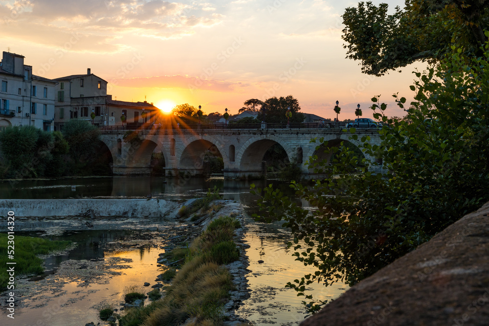 Soleil couchant sur le pont romain transversant le Vidourle à Sommières