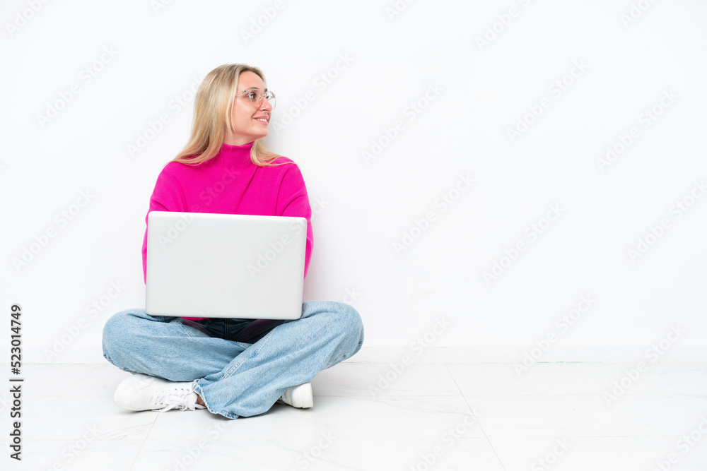 Young caucasian woman with laptop sitting on the floor in lateral position Young caucasian woman with laptop sitting on the floor in lateral position