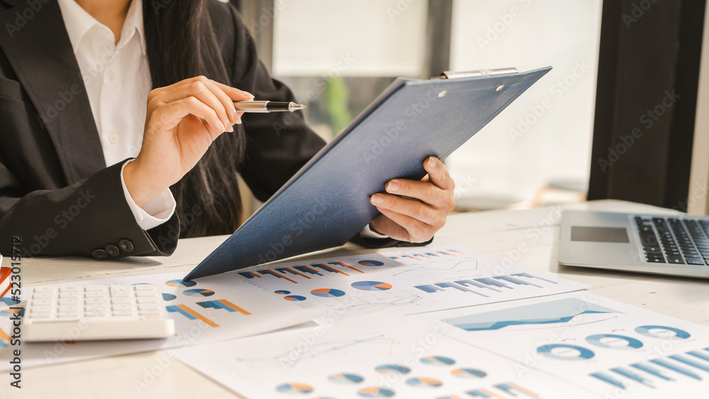 Close up of Hand business woman holding pen pointing on chart summary report and calculate finance. Close up of Hand business woman holding pen pointing on chart summary report and calculate finance.