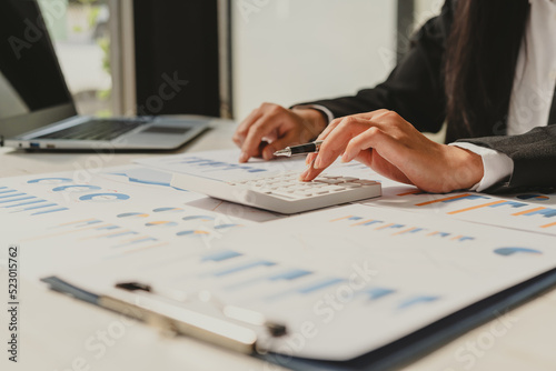 Close up Business woman using calculator and laptop for do math finance on wooden desk in office and business working background, tax, accounting, statistics and analytic research concept