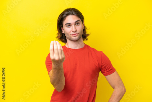 Caucasian handsome man isolated on yellow background making Italian gesture