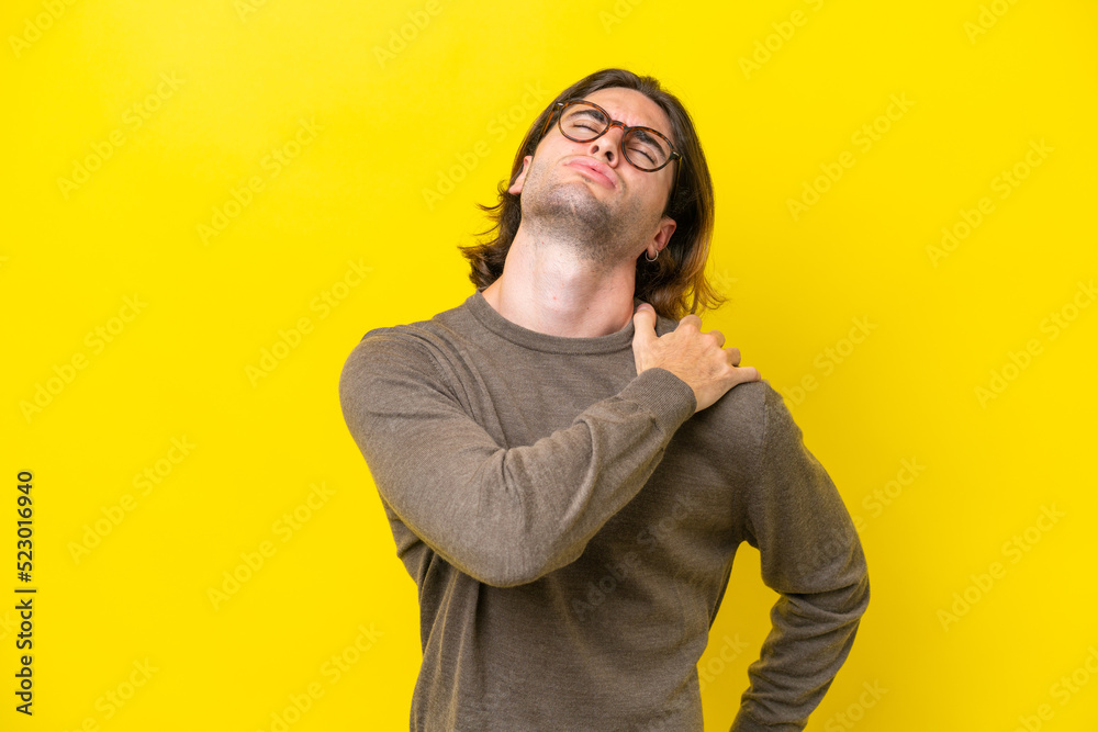 Fototapeta premium Caucasian handsome man isolated on yellow background suffering from pain in shoulder for having made an effort