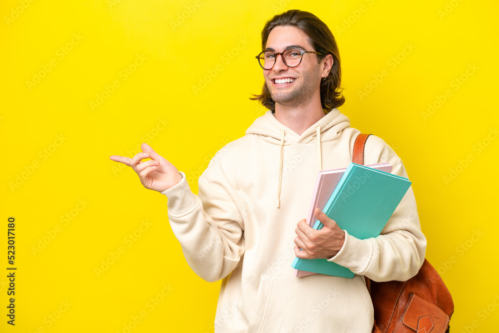 Young student handsome man isolated on yellow background pointing finger to the side