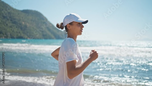 Yclose up oung woman exercising outdoor running with a sea background. When sun raises in Turkey in summer, Concept healthy running and outdoor exercise, Tracking dolly shot. go everywhere photo