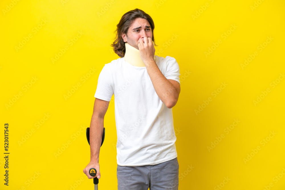 Young handsome man wearing neck brace and crutches isolated on yellow background having doubts Young handsome man wearing neck brace and crutches isolated on yellow background having doubts