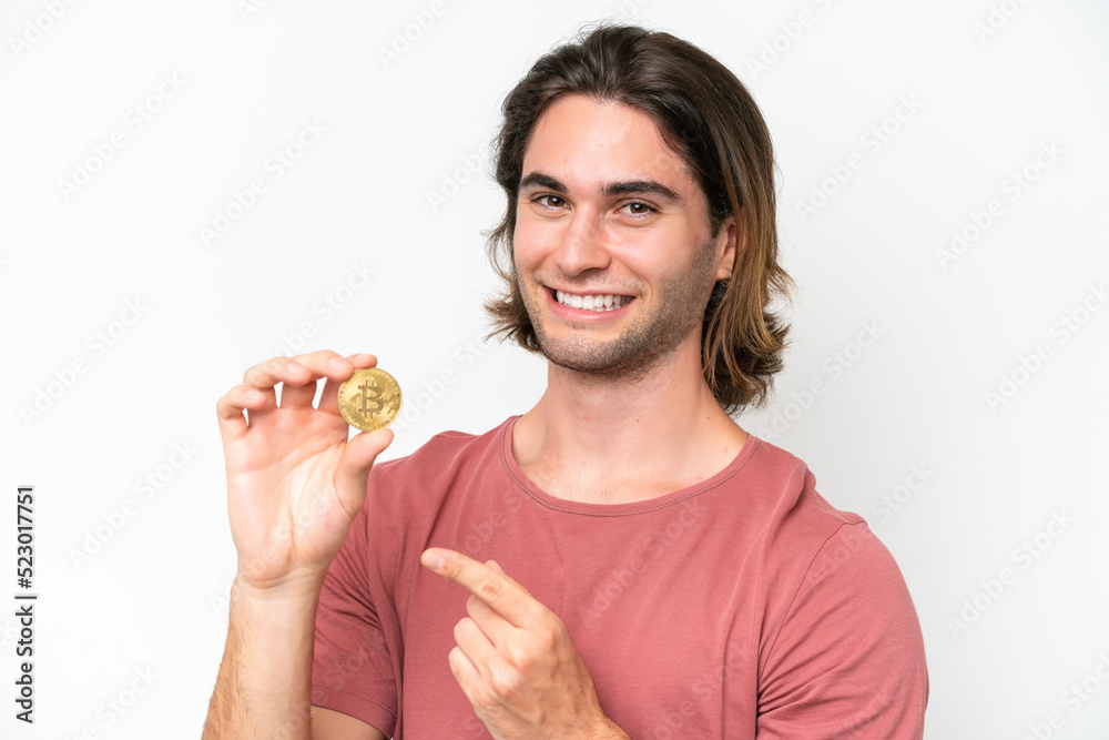 Young handsome man holding a Bitcoin isolated on white background and pointing it Young handsome man holding a Bitcoin isolated on white background and pointing it