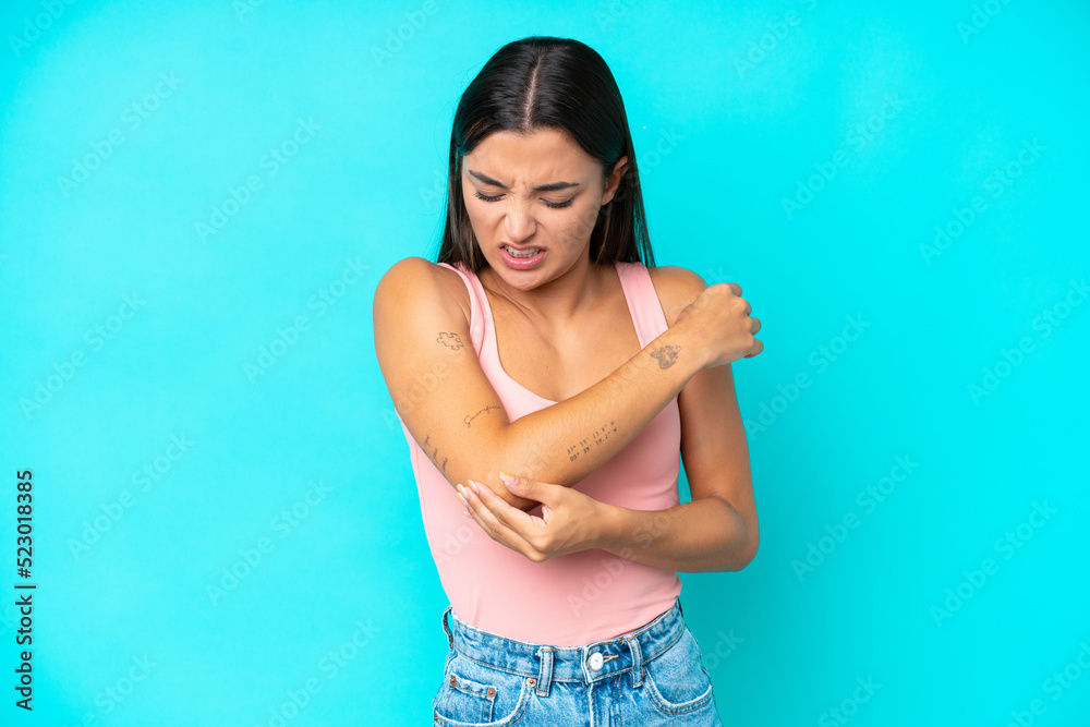 Young caucasian woman isolated on blue background with pain in elbow Young caucasian woman isolated on blue background with pain in elbow