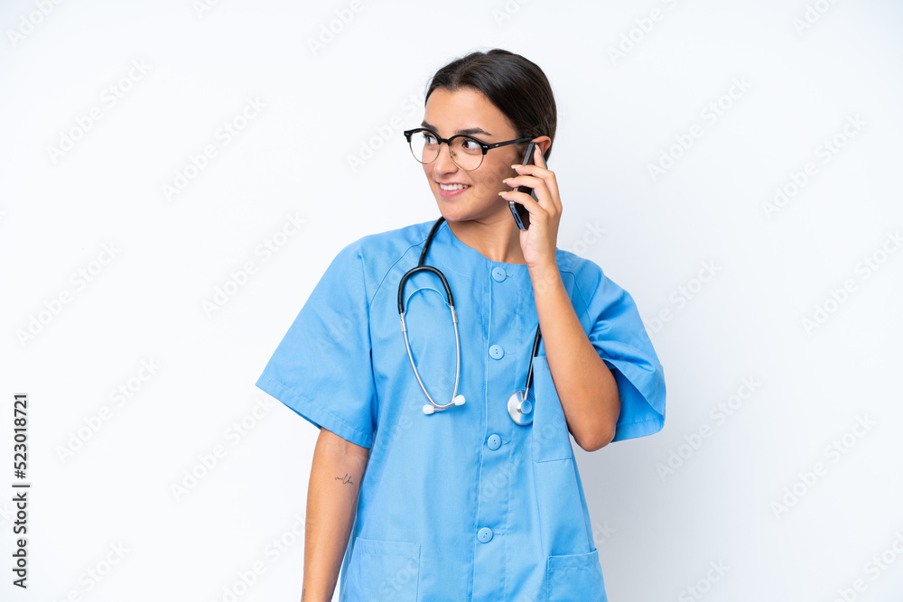 Young nurse woman isolated on white background keeping a conversation with the mobile phone with someone Young nurse woman isolated on white background keeping a conversation with the mobile phone with someone