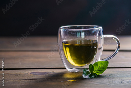 Herbal mint tea cup Transparent glass dark background wooden table still life honey bowl metal kettle teapot spoon cozy