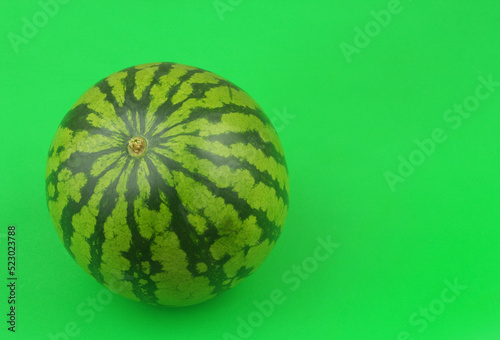 Whole watermelon on green background with room for text.