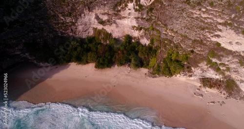 Aerial shot of beach with turquoise water down steep cliff and headland
