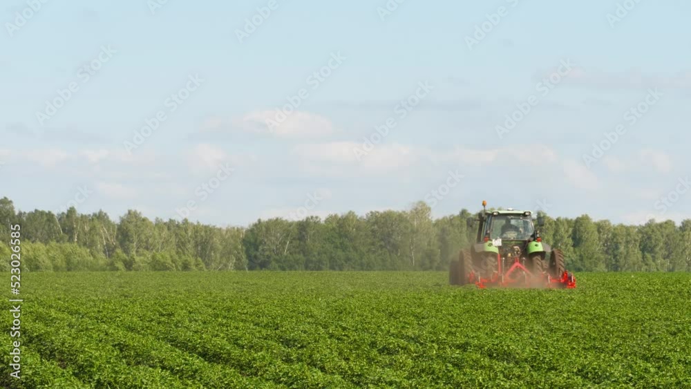 Green agricultural tractor works in the field, summer. Agribusiness and agriculture concept Green agricultural tractor works in the field, summer. Agribusiness and agriculture concept