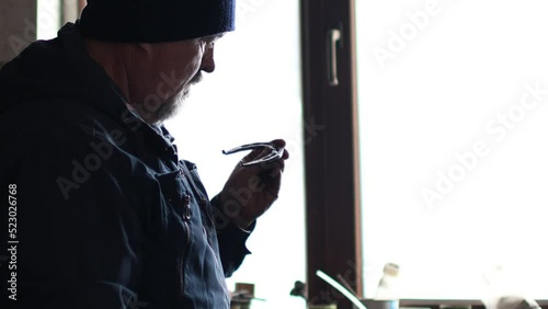 Blacksmith forges and checking tempered metal horseshoe in jar with water at forge.